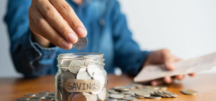 Woman putting money into a jar.