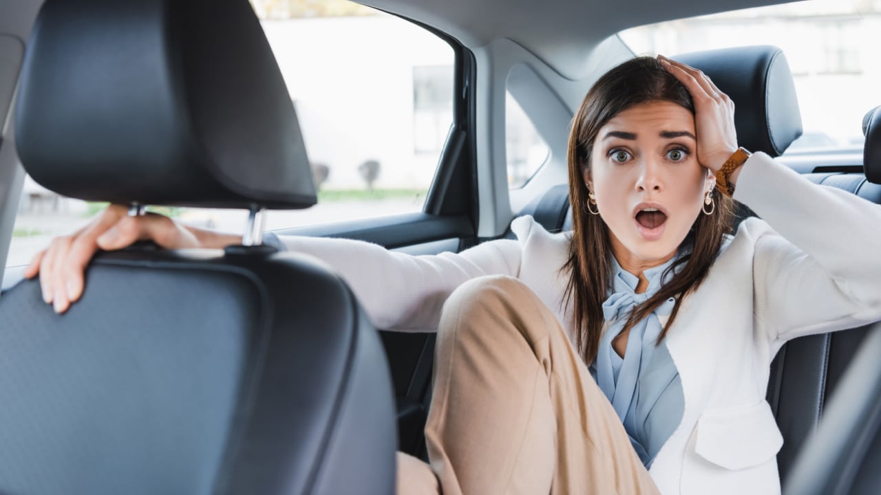 Surprised woman in the backseat of a car.