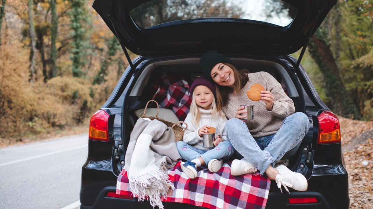 Mother and daughter eating picnic in car