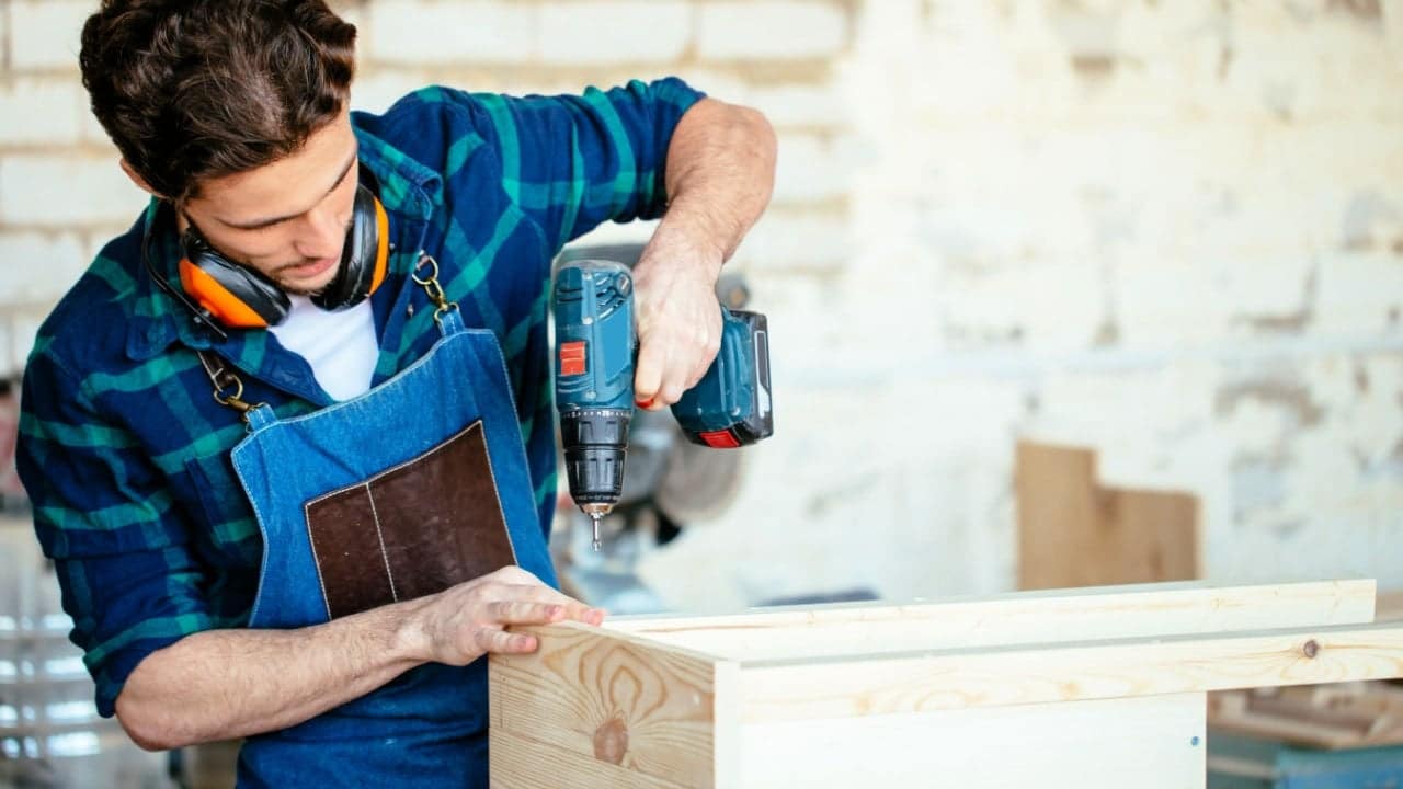 Carpenter drills a hole with an electrical drill