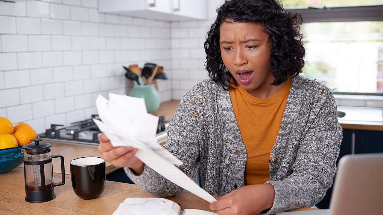 A young multi-ethnic woman is shocked when reviewing household expenses bills