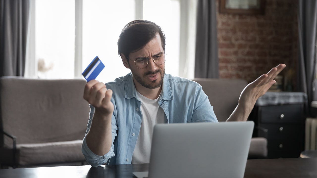 Annoyed frustrated bank customer man using laptop, reading message, notice about problem with credit card, blocked account, counting expenses, loss, getting financial overspending, bankruptcy