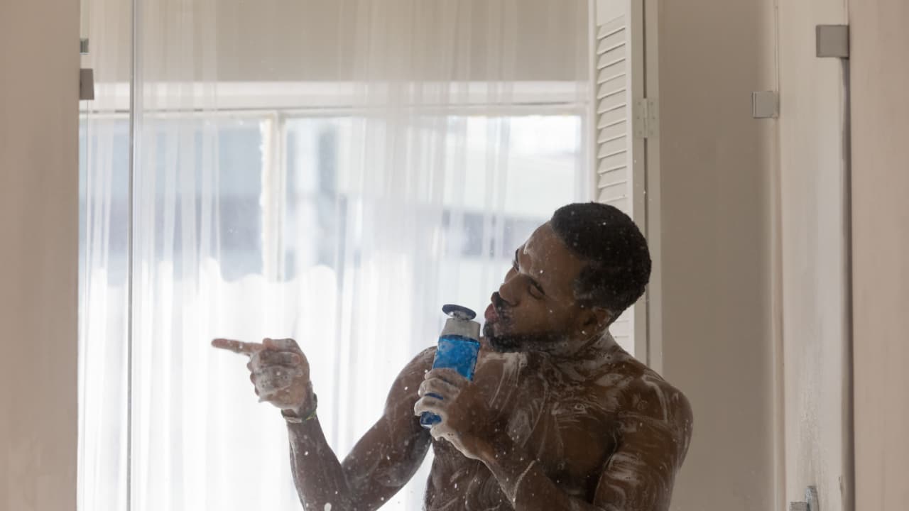 Man showering holding body wash