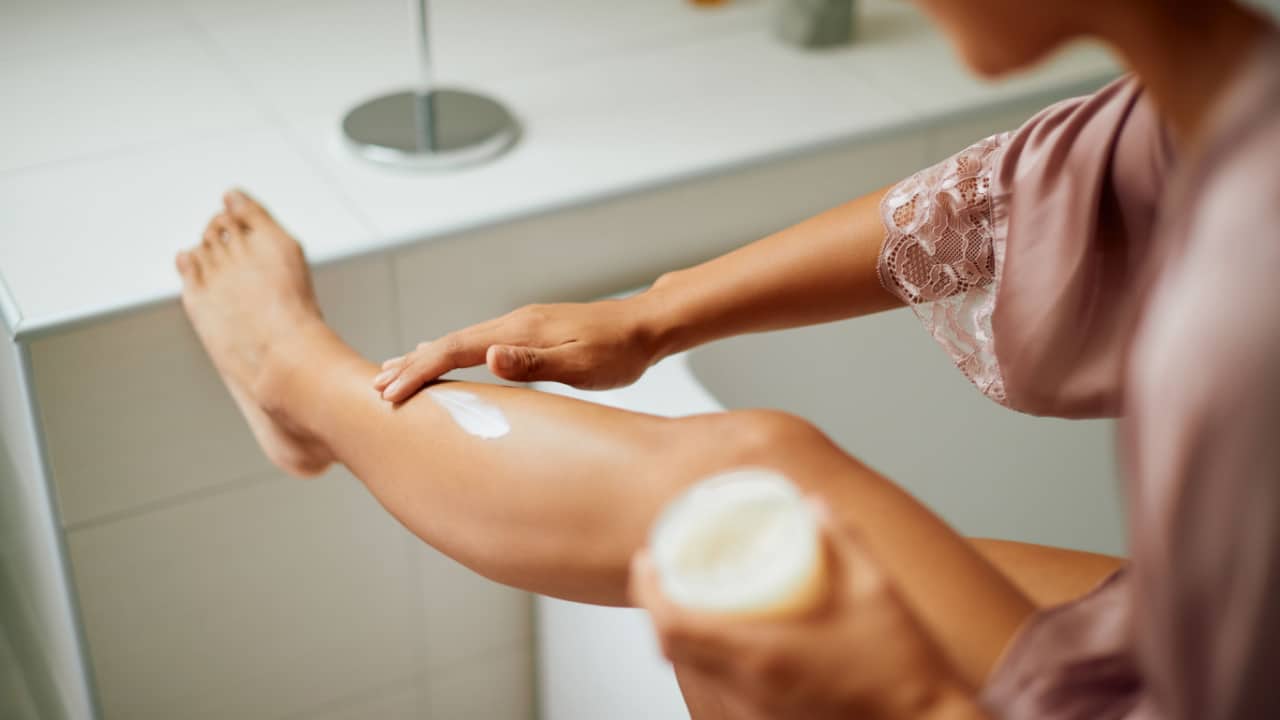 Woman applying body lotion to legs